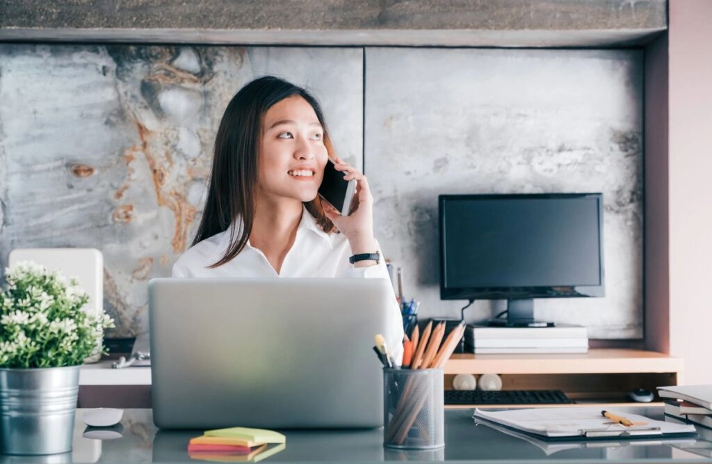 Business woman talking on the phone in front of a laptop on the desk.
