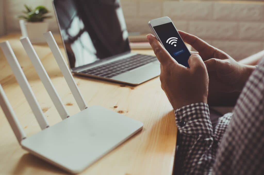 Technician testing a wireless network installation by connecting a smart phone to the network.