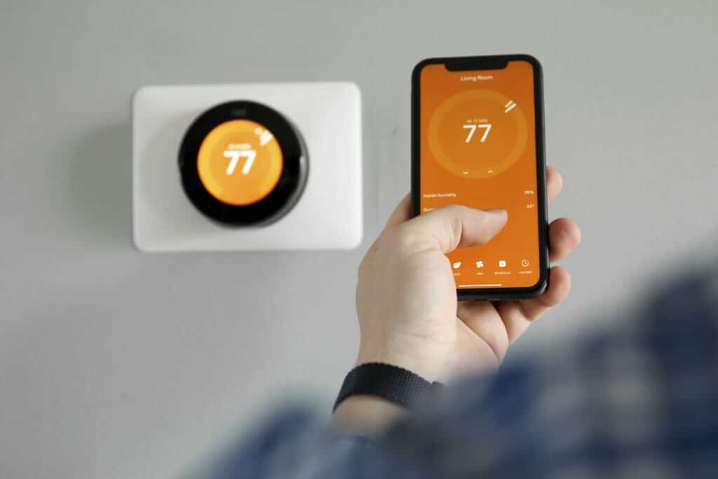 Technician performing professional smart thermostat installation on wall.