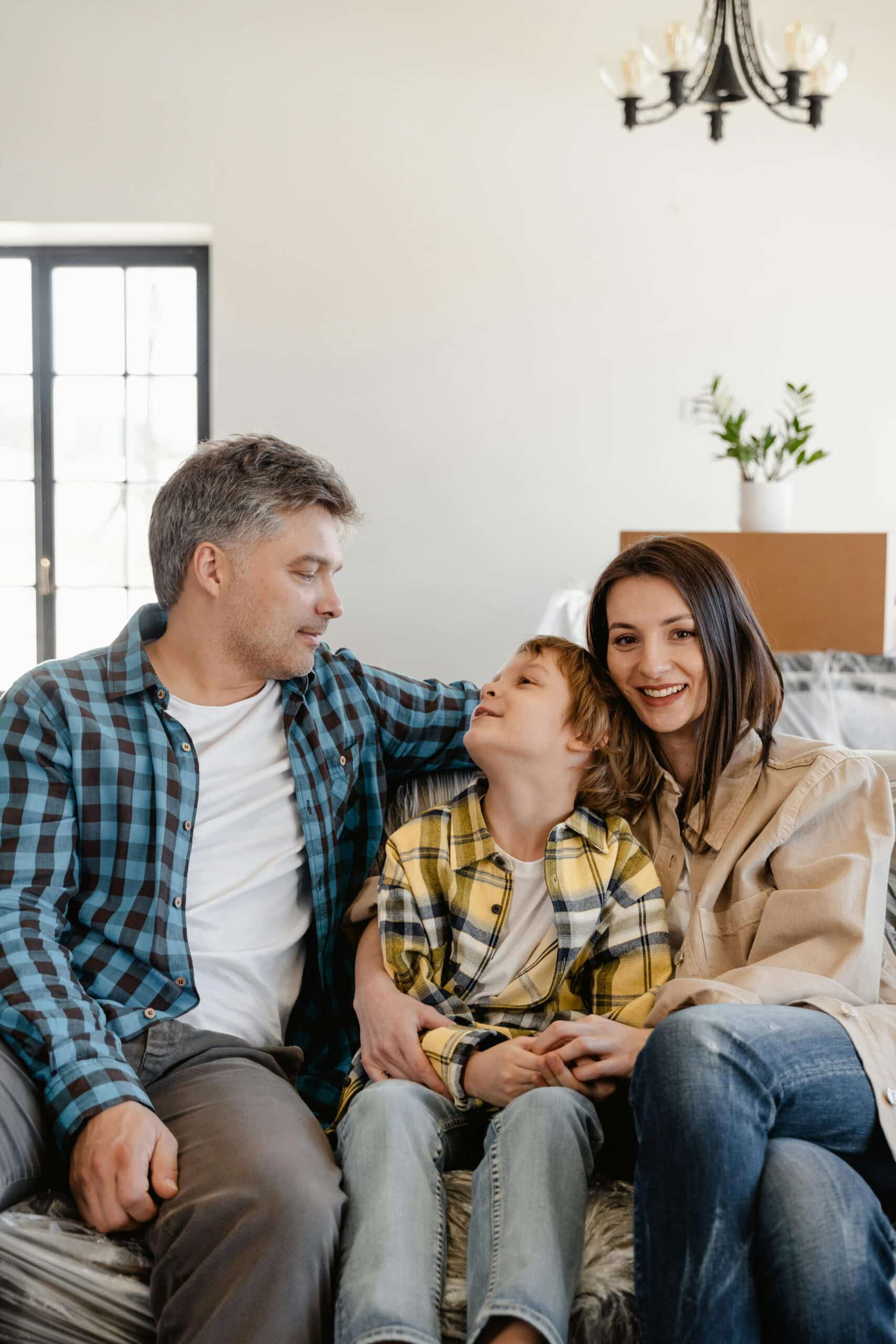 Family of 3 sitting together on a couch.