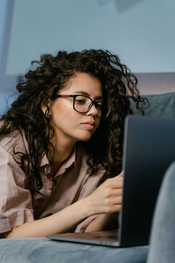 Woman lying down on couch using laptop.