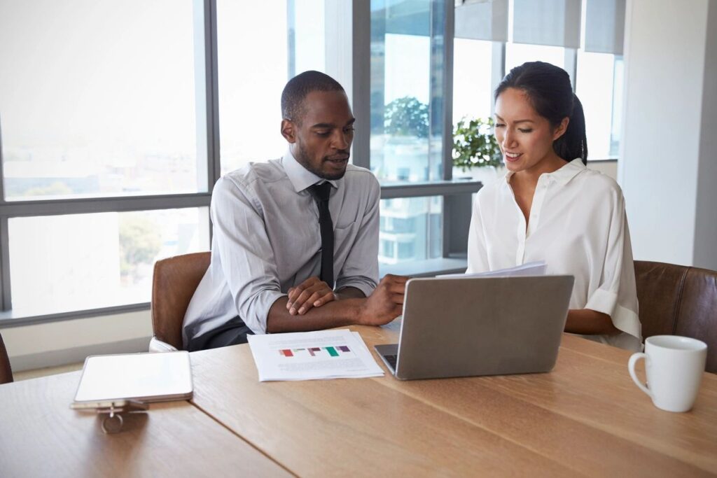 Two business people conversing at a conference table.