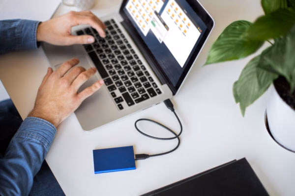 Data backup in progress on laptop with external storage drive Laptop connected to external hard drive with file transfer in progress