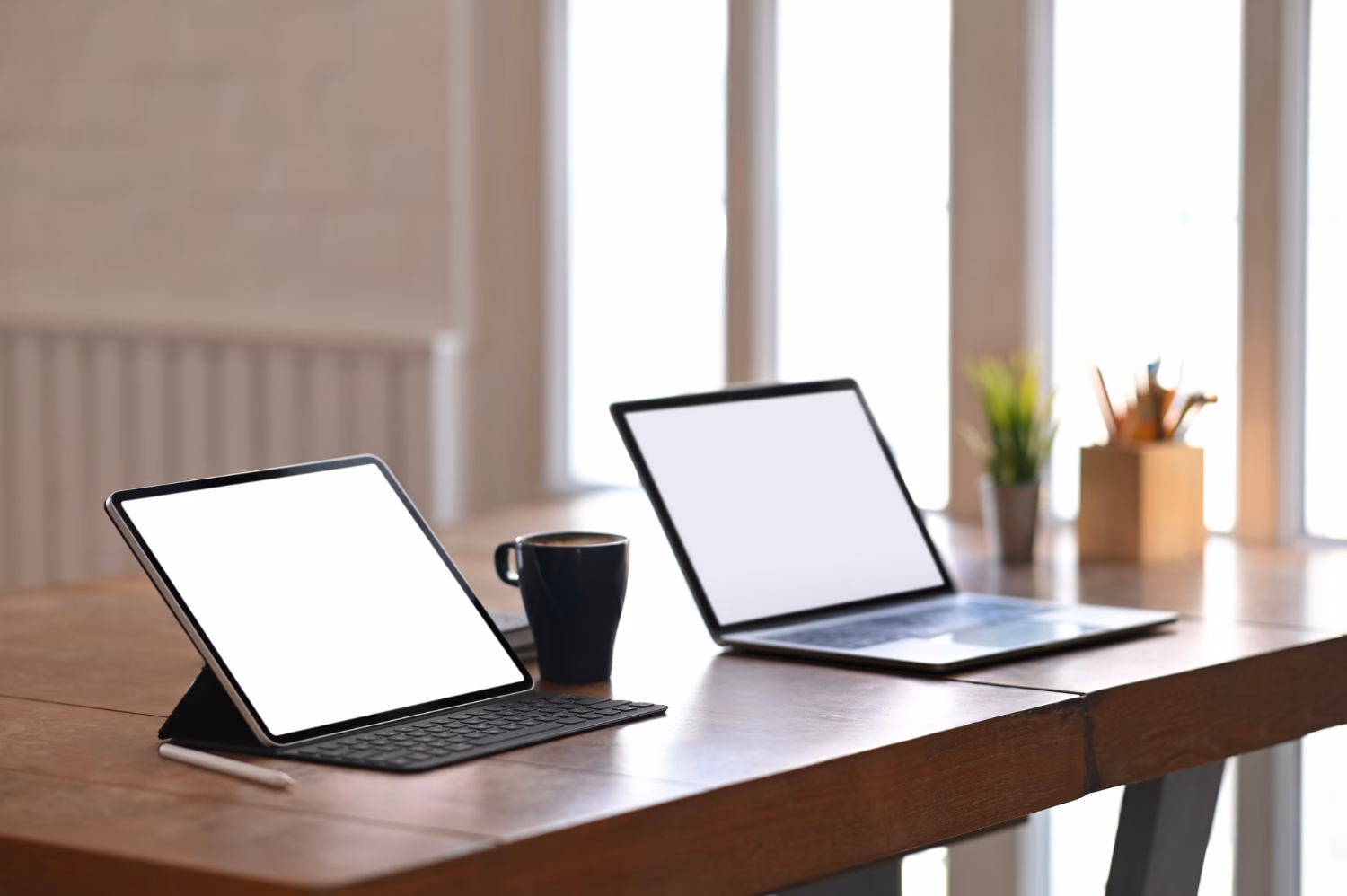 Tablet and laptop side-by-side on a desk for productivity comparison.